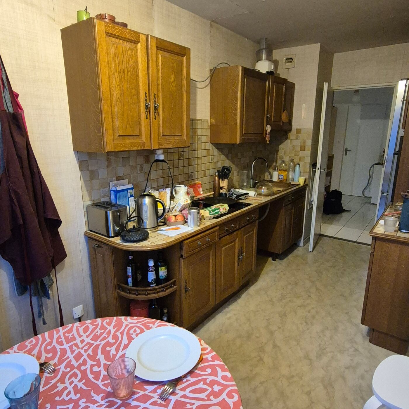 La cuisine de Catherine avant travaux : meubles en bois foncé, plan de travail encombré, ambiance vieillissante, en décalage avec le reste de l'appartement