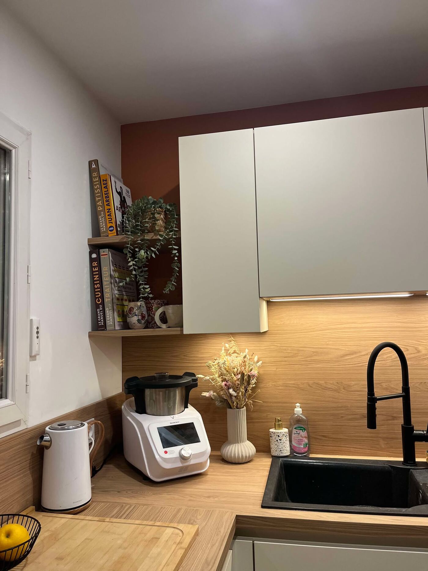 La cuisine de Lucie et Axel après travaux : façades blanc mat, plan de travail bois, mur terracotta, ambiance lumineuse et chaleureuse