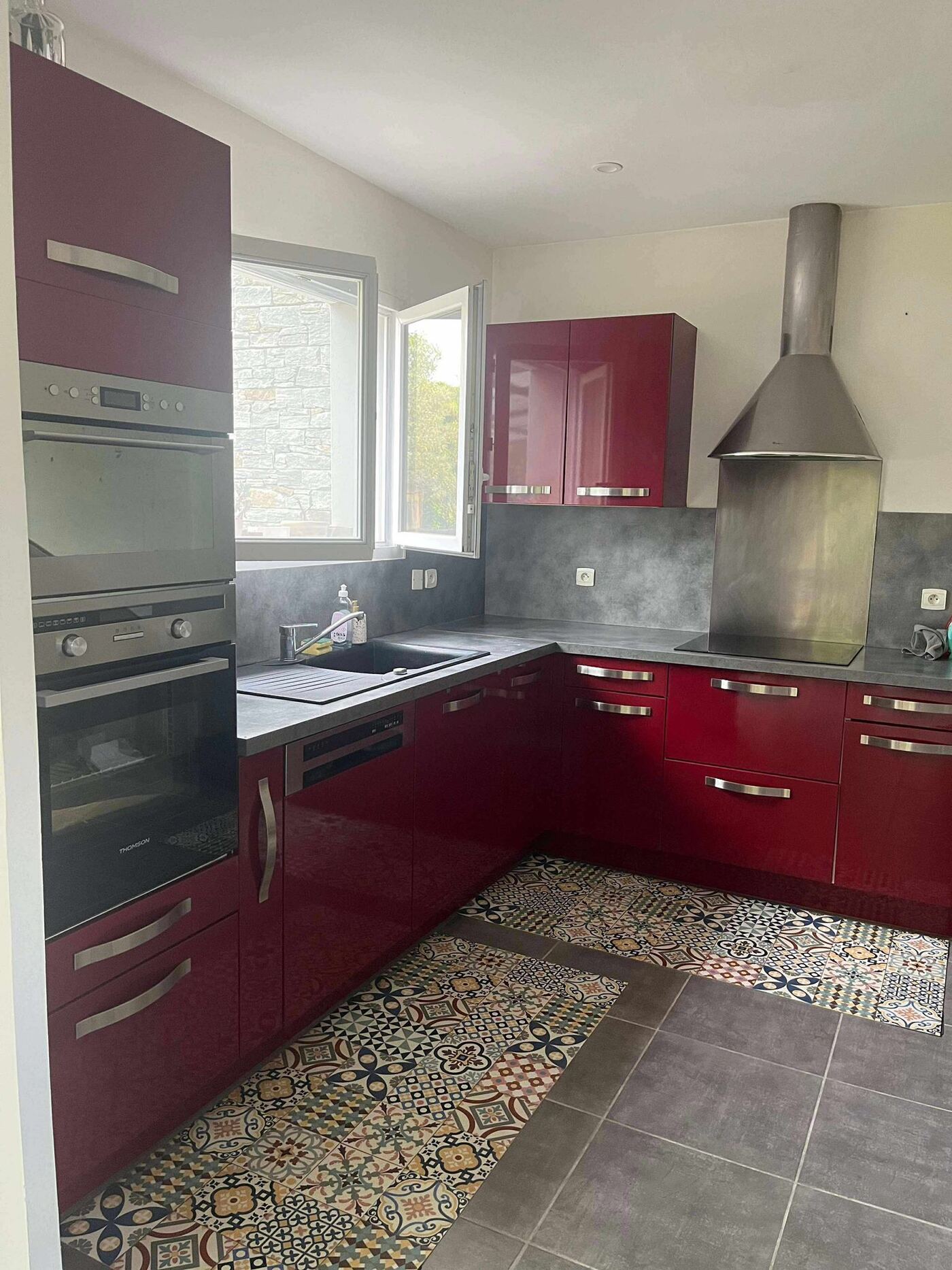 La cuisine de Lucie et Axel avant travaux : façades rouge bordeaux laquées, plan de travail effet béton, ambiance fermée et datée