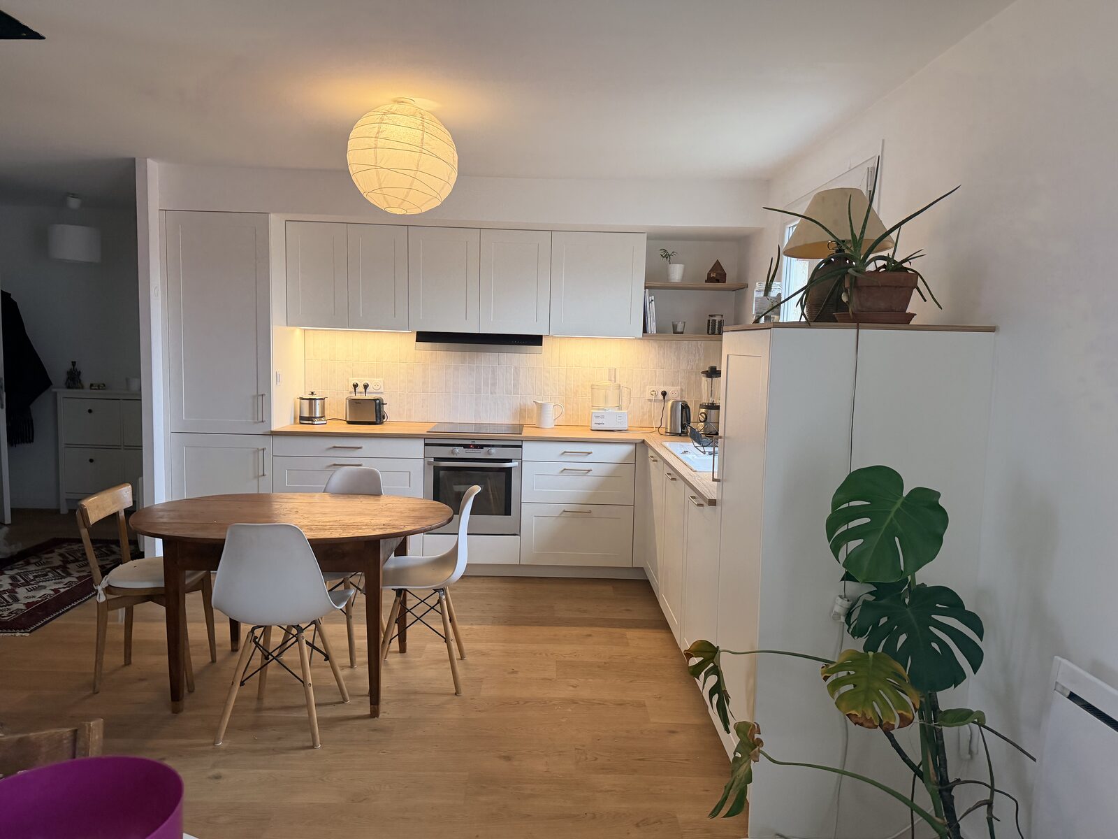 La cuisine de Véronique après travaux : façades blanc shaker, plan de travail bois, crédence claire, ambiance lumineuse