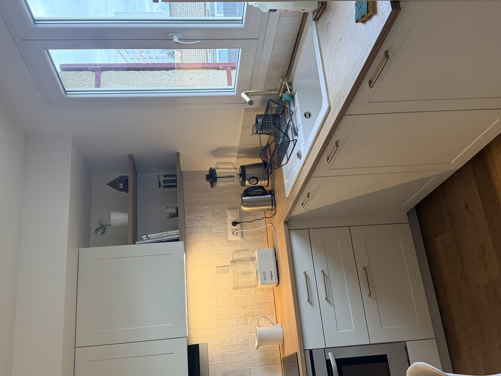 Vue de la cuisine en L blanche avec table en bois